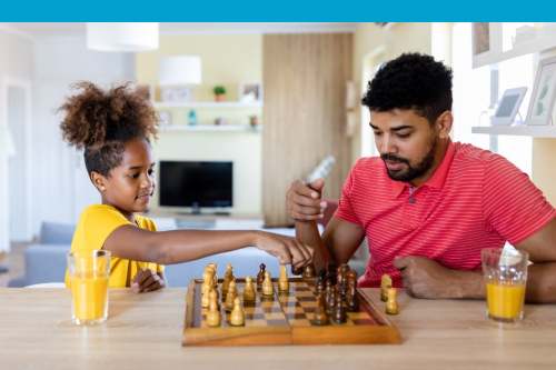 Adult male and female child playing chess together.