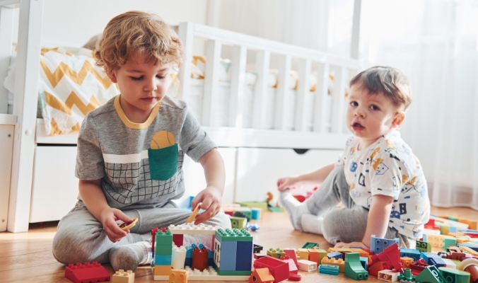 Two toddlers playing with building blocks